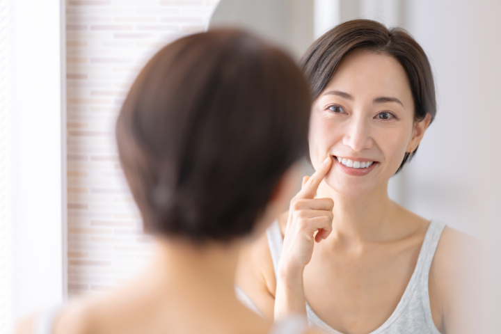 歯周病を治療して健康になった歯茎を鏡で確認する女性