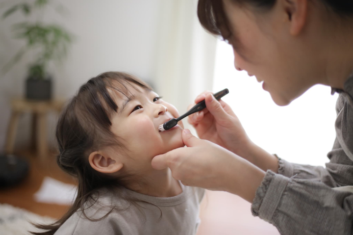 母親に歯磨きしてもらって嬉しそうな女の子