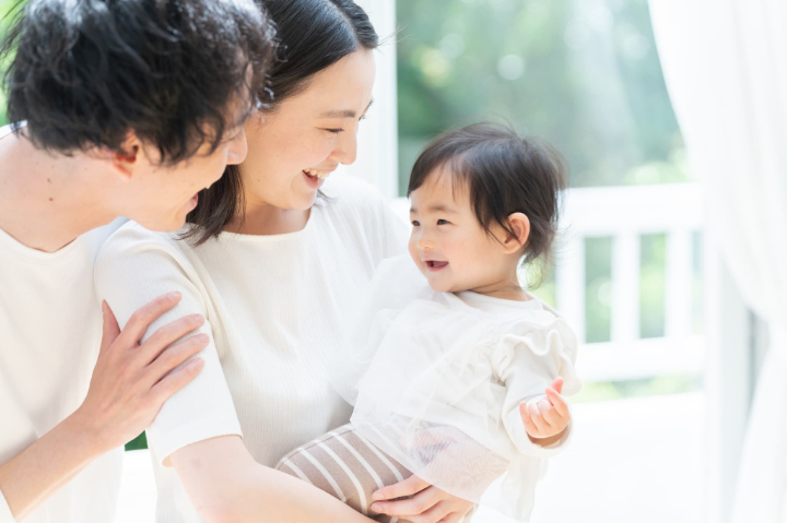 お母さんに抱っこしてもらってご機嫌な赤ちゃんとあやす父親