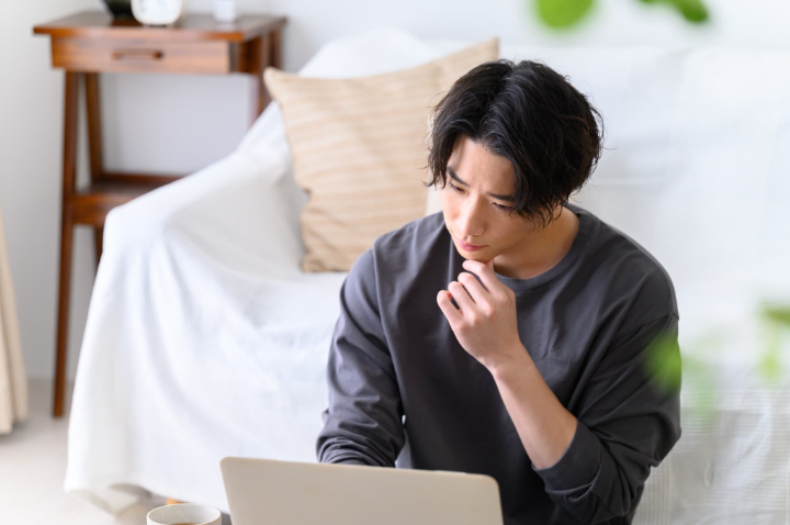 審美歯科治療に保険は適用されるのかパソコンで調べる男性