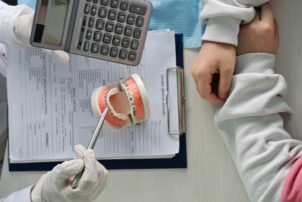 ワイヤー矯正の模型を示しながら費用の説明をする歯科医師