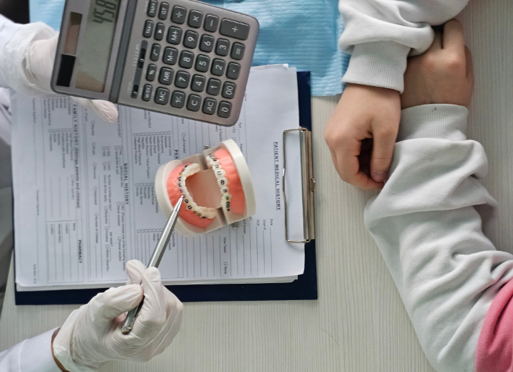 ワイヤー矯正の模型を示しながら費用の説明をする歯科医師