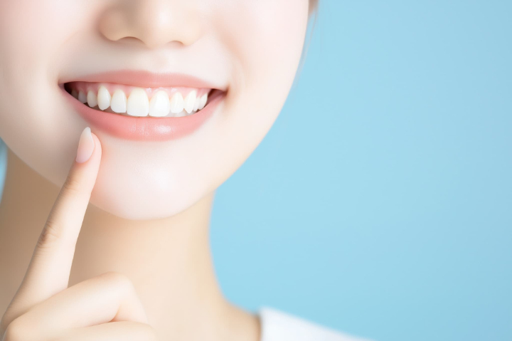 白くてきれいな歯を指さす女性の口元