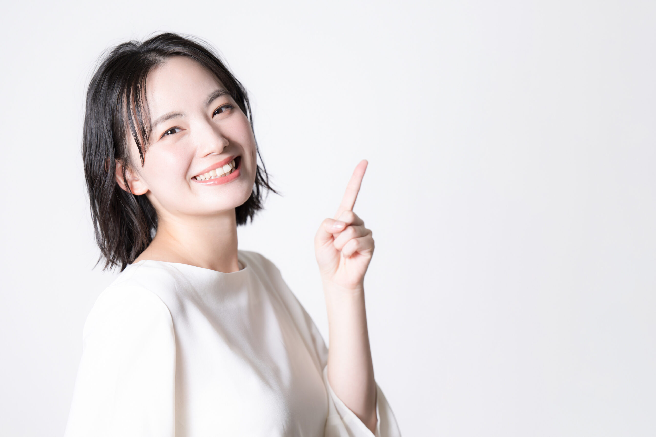 笑顔オススメする若い女性のクローズアップ　指さしのポイントポーズ