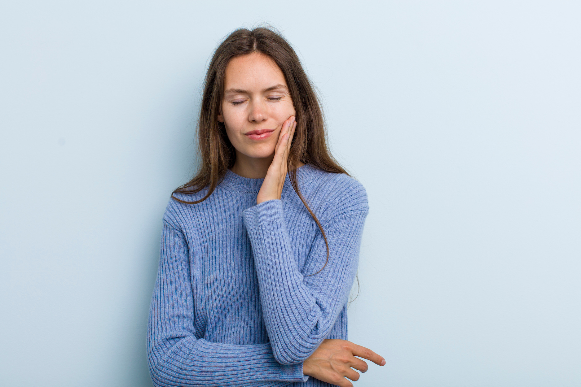 holding cheek and suffering painful toothache, feeling ill, miserable and unhappy, looking for a dentist