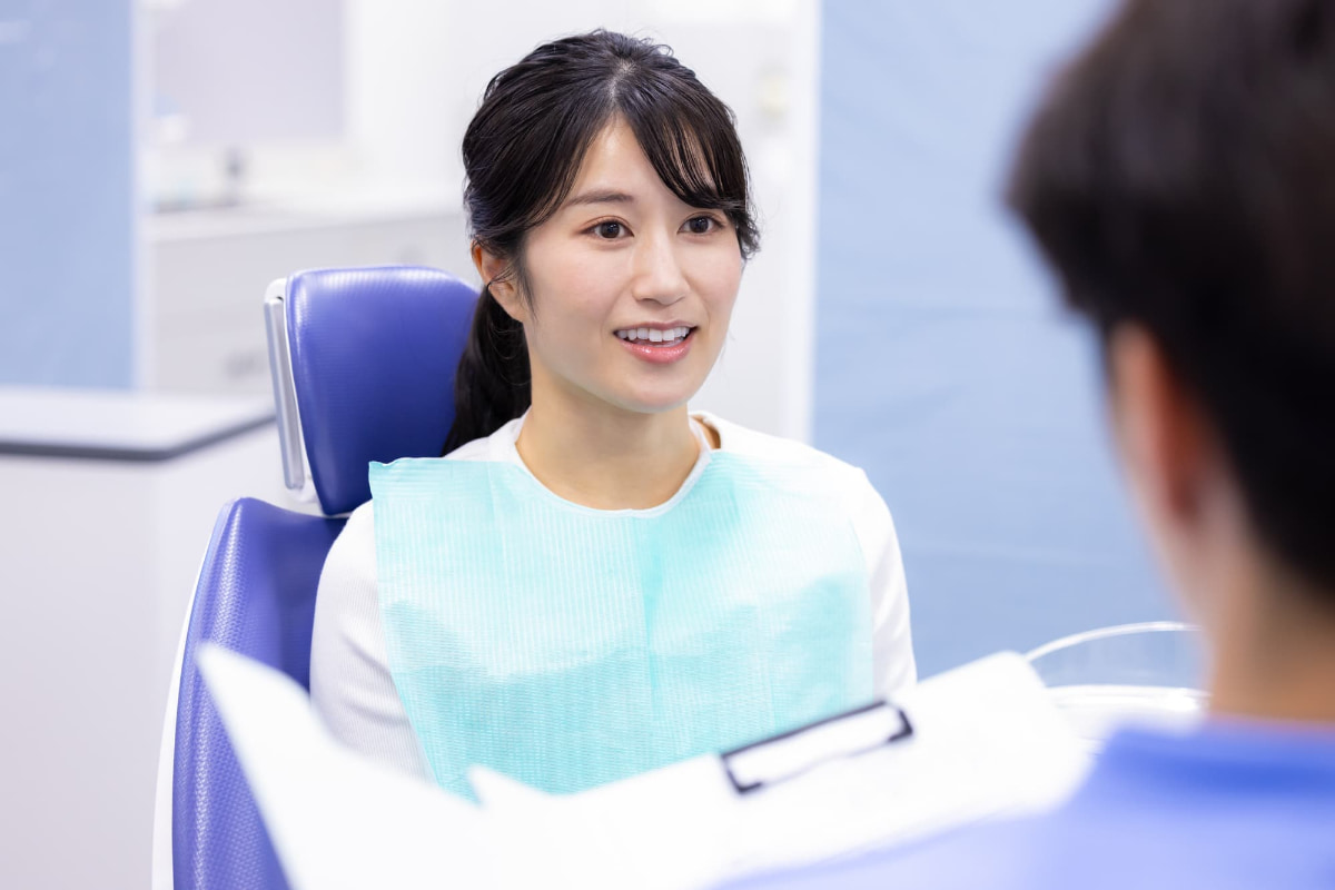 矯正治療後に後戻りを起こして歯科医に相談する女性